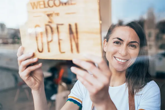 Quick Tips to Save on Your Utility Bill - Woman turning shopfront sign to 'Open for Business'
